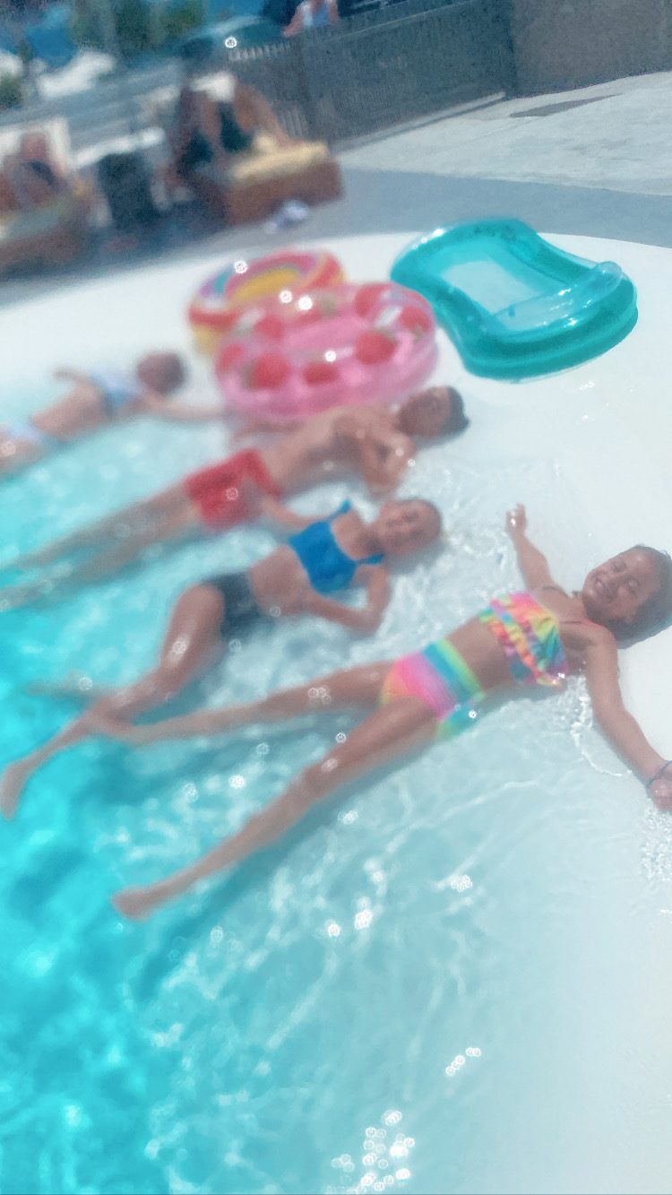 Children floating on their backs in a bright turquoise pool on a sunny day