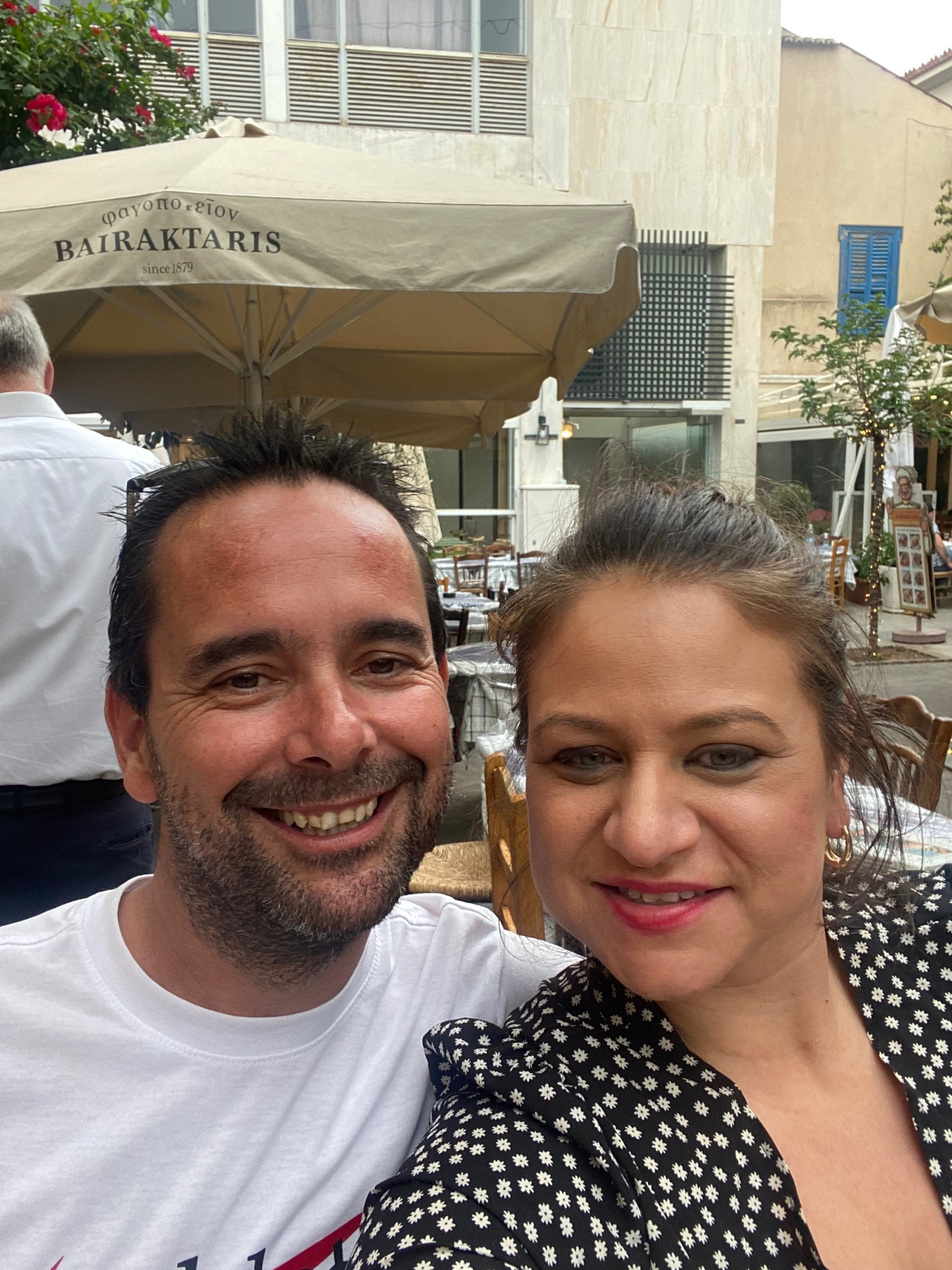 The two of us at a taverna table under a shady umbrella in Greece