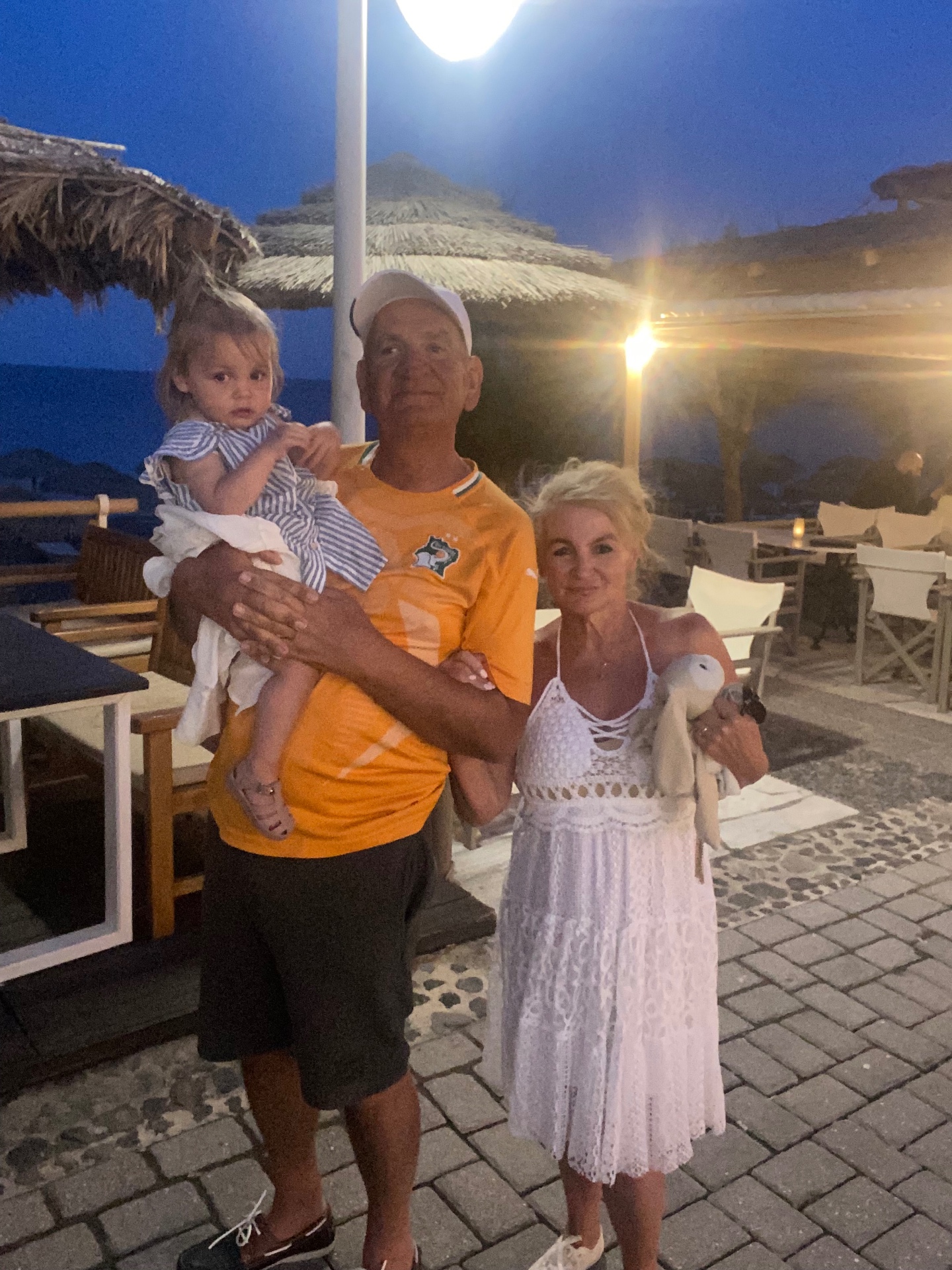 Family holding the baby at a seaside taverna on a warm Greek evening