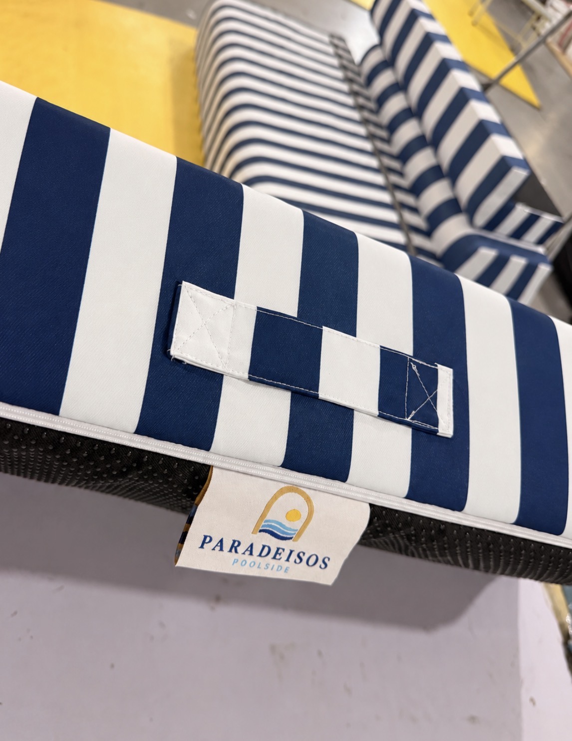 Close view of the Akti cushion's carry handle and woven Parádeisos Poolside label